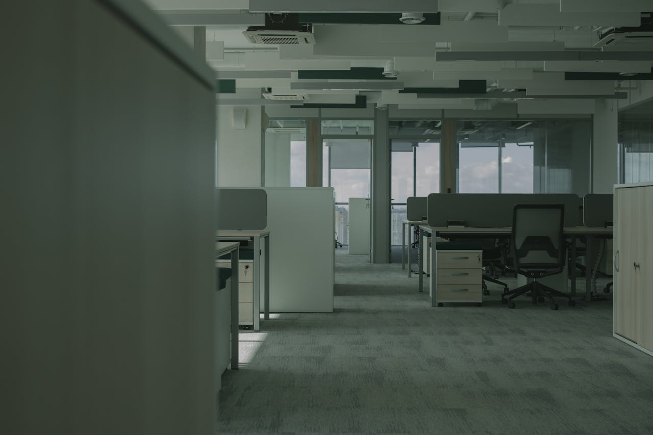 Spacious empty office featuring modern desks, chairs, and partitions.